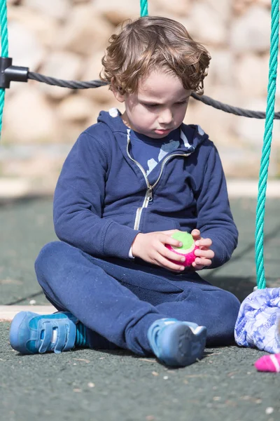 Primer plano del niño rubio sentado en el patio de recreo —  Fotos de Stock