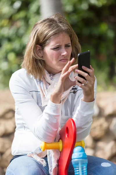 Retrato de mujer joven con teléfono celular en el patio de recreo — Foto de Stock