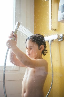 Duş başının üstüne dökülen küçük çocuk portresi