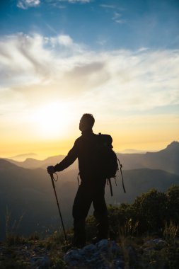 Dağlarda dağcı izlerken günbatımı
