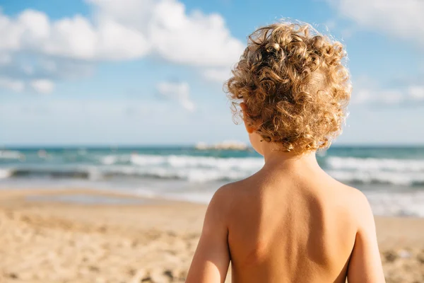 Achteraanzicht van topless jongen op strand — Stockfoto
