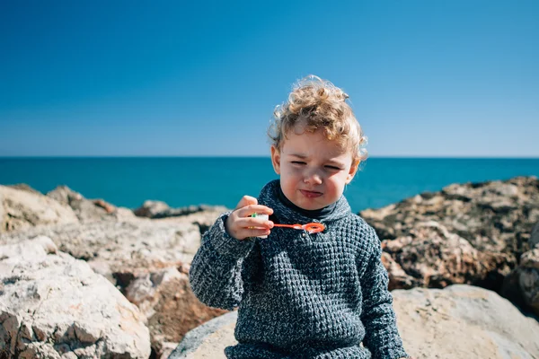 Boy making faces blowing soap bubbles — Stock Photo, Image