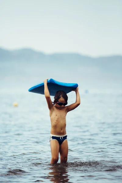 Criança com bodyboard azul em pé no mar — Fotografia de Stock