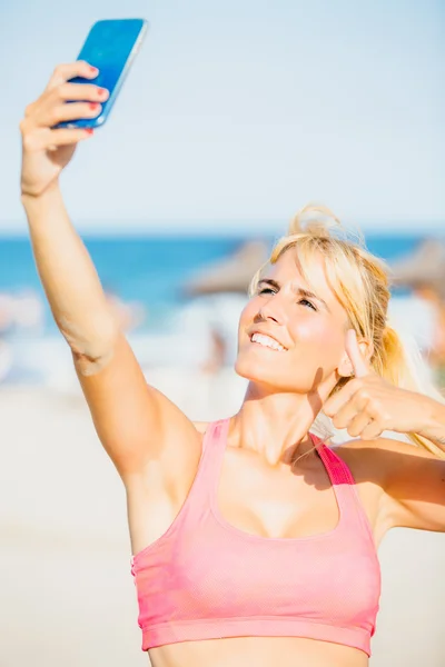 Leende idrottskvinna tar selfie på stranden — Stockfoto