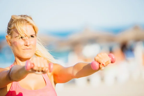 Mujer haciendo ejercicio con pesas en la playa — Foto de Stock