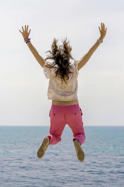 Mujer joven saltando por el mar — Foto de Stock