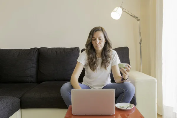 O femeie tânără care folosește un laptop acasă — Fotografie, imagine de stoc