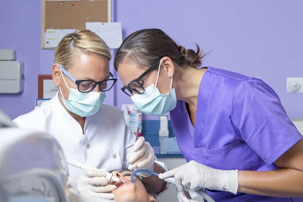 Dentista feminina trabalhando com seu assistente — Fotografia de Stock