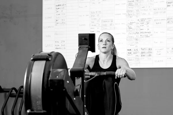 Mujer en la máquina de remo crossfit workou — Foto de Stock