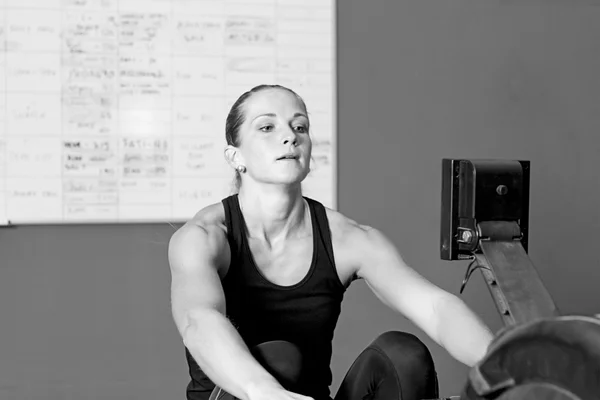 Young woman on rowing machine - crossfit workou — Stock Photo, Image