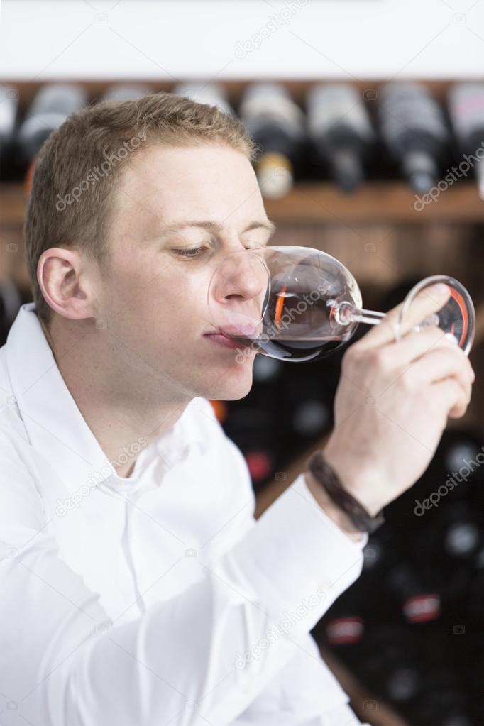 man tasting a red wine glass