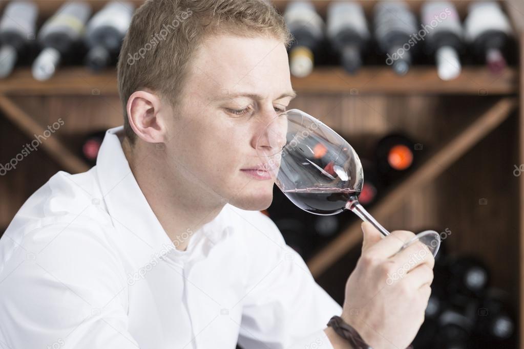 young man smelling a glass of red win