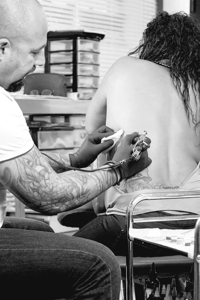 Tattoo artist tattooing a bac — Stock Photo, Image