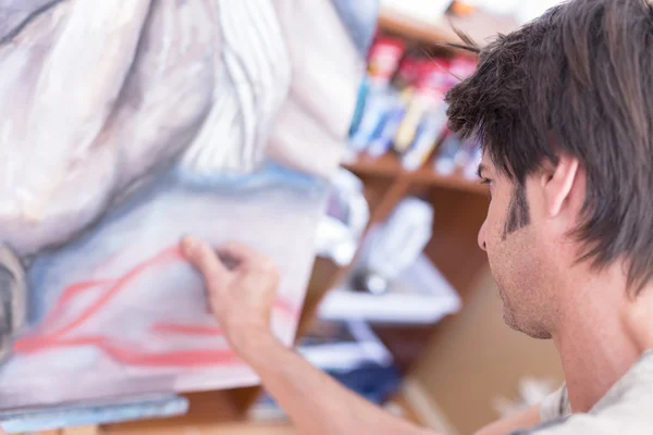 Young man painting with chalk on canvas - painting session — Stock Photo, Image