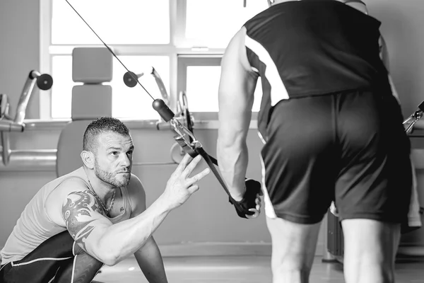 Personal trainer helping man with dorsal exercise — Stock Photo, Image