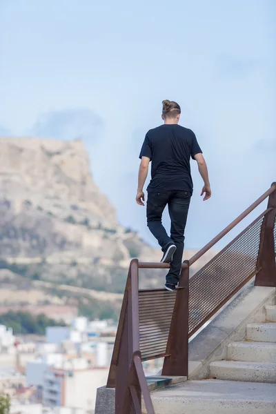 Rückansicht eines jungen Athleten, der am Geländer geht — Stockfoto