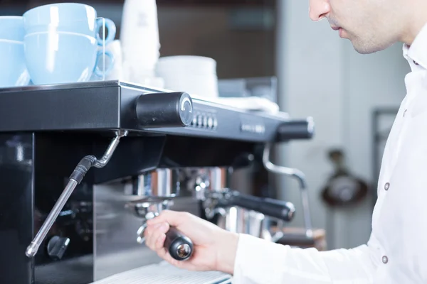 Bartender puts holder in coffee machine — Stock Photo, Image