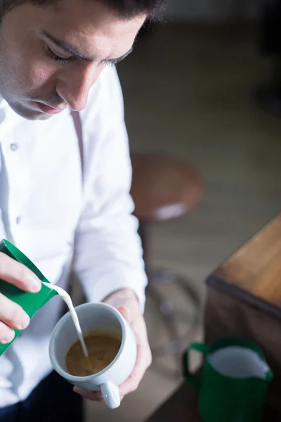 Barista wylaniem piany mleka w kawie — Zdjęcie stockowe