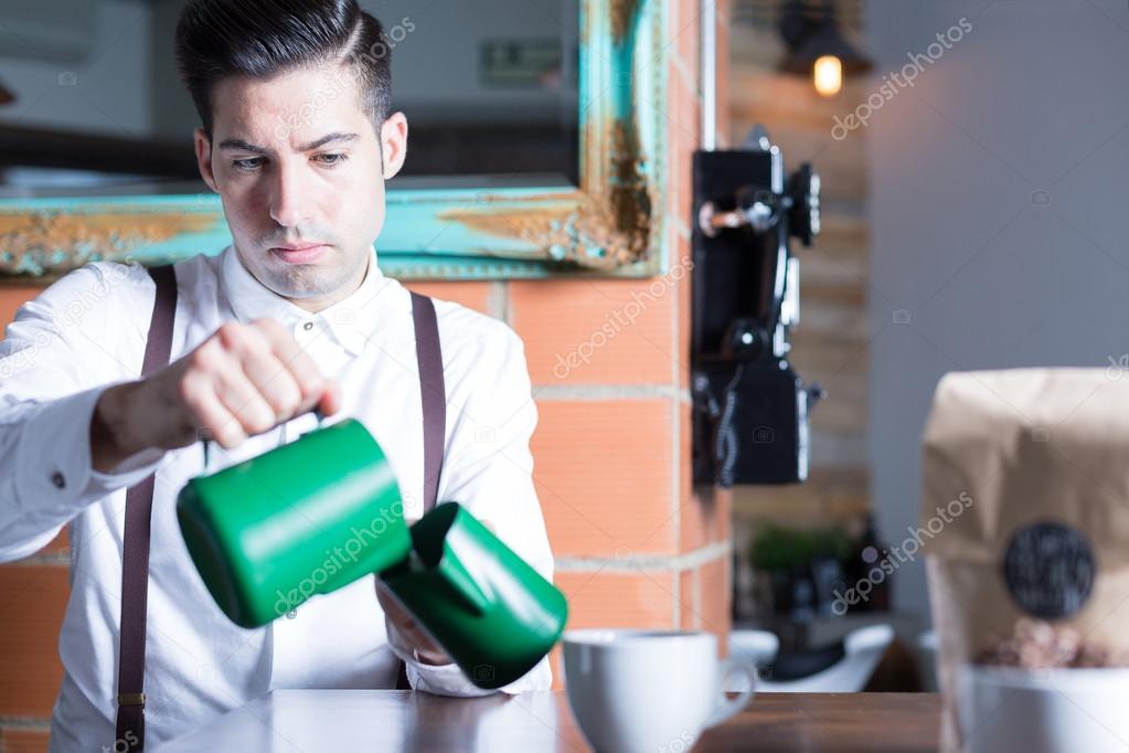 Barista pouring milk from one pitcher to another
