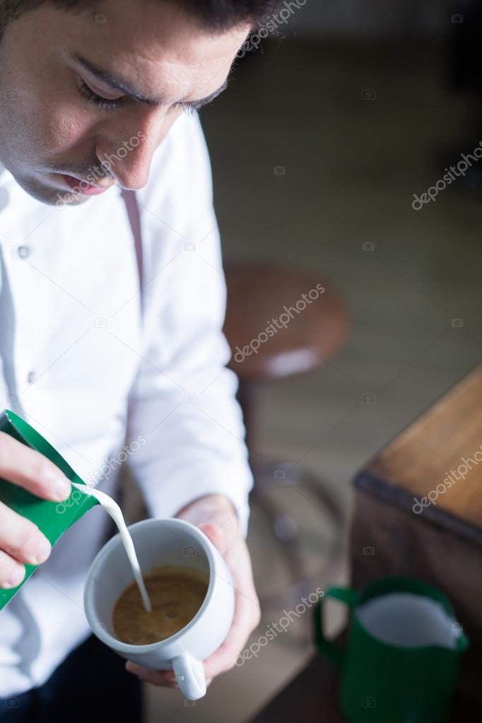 Barista pouring froth milk in coffee