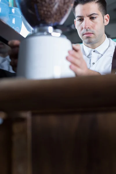 Männlicher Barkeeper mahlt Kaffeebohnen — Stockfoto