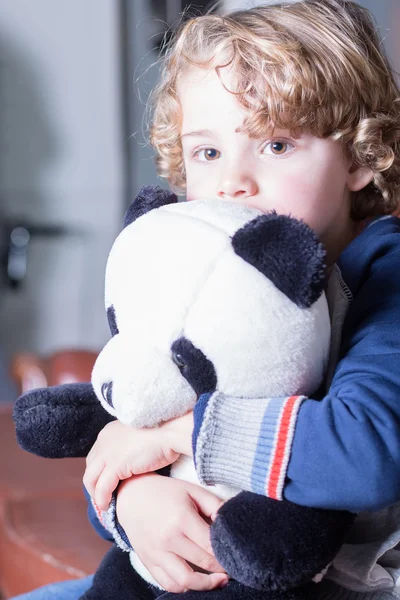 Primo piano di bello ragazzo biondo con i capelli ricci abbracciando panda giocattolo — Foto Stock