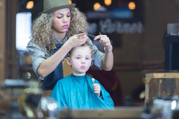 Reflejo de espejo de mujer joven cortando pelo de niño —  Fotos de Stock