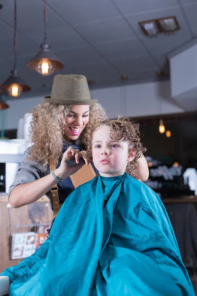 Young woman laughing while cutting boy hair — Stock Photo, Image