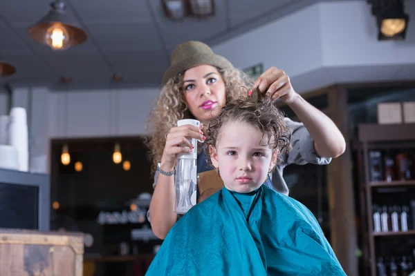 Young woman spraying boy hair — Stock Photo, Image