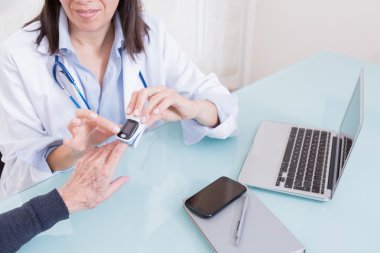 Doctor using finger oximeter with patient clipart