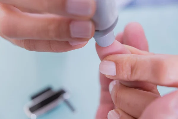 Doctor and patient using lancing device — Stock Photo, Image