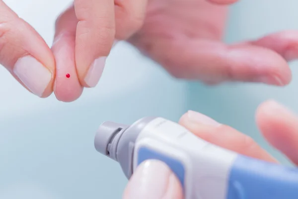 Médico sosteniendo el latigazo y el dedo con gota de sangre — Foto de Stock