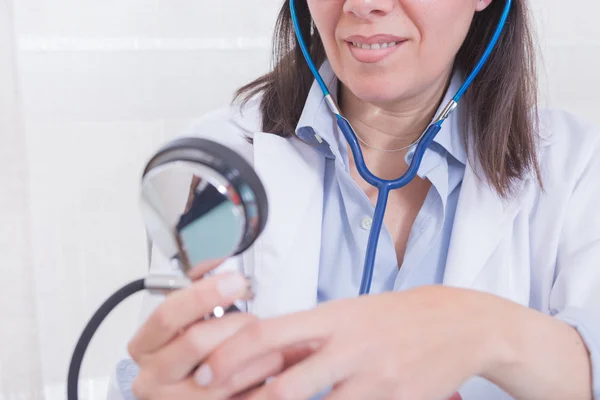 Smiling doctor looking at manometer — Stock Photo, Image
