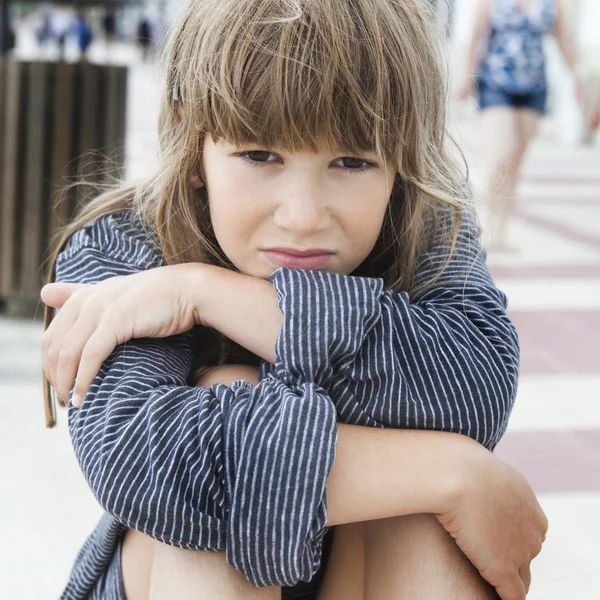 Malá dívka, která nosí proužkované tričko jejího otce, sedící na lavičce. Problémy s rodiči — Stock fotografie