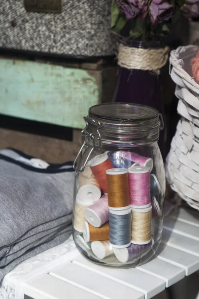 Glazen pot met een spoel van draad — Stockfoto