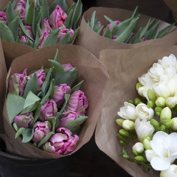 Bukiety z czerwone tulipany i biała frezja w papier pakowy — Zdjęcie stockowe