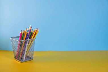 Tutucudaki kalemler mavi arka planda izole edilmiştir. Düz yerde, üst tarafta. Uzayı kopyala Okula dönelim. Eğitimde