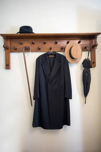 旧式的黑色长大衣 草帽和雨伞挂在旧货店的衣架上 — 图库照片