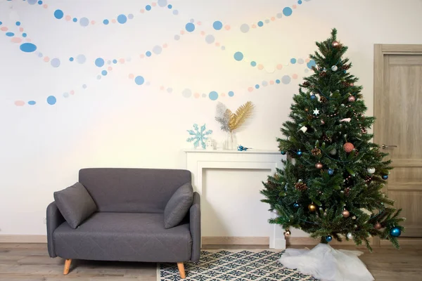 在一棵圣诞树的背景下 用灰色的手工纸包着平底锅里的波塞蒂亚 墙上的花环和摇曳的马背上的萤火虫 — 图库照片
