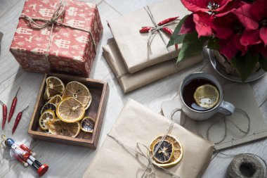 Mango ağacından yapılmış ahşap bir kutuda kurumuş turuncu halkalar, el işi kağıda sarılmış ve sicimle bağlanmış, hediyeler, limonlu çay fincanı. Noel için hazırlanıyorum. Boşluğu kopyala