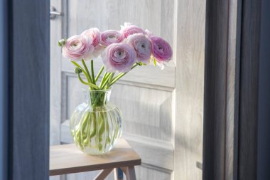 Kapının önündeki yüksek taburede pembe İran düğün çiçekleri. Odanın dekorasyonu.