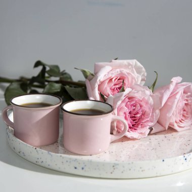 Rose White Pembe O 'hara. Kahvaltı masasındaki beyaz tepside iki küçük fincan kahveyle pembe güller.