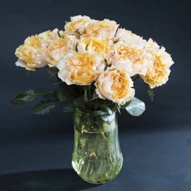 Siyah arka planda eski yeşil cam vazodaki turuncu gül buketi. Kare kare