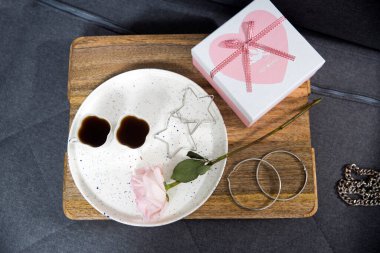 Rose White Pembe O 'hara. İçi hediye dolu bir kutu tepside, iki bardak çay ve küpe - sehpada Sevgililer Günü hediyesi..