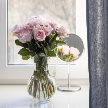 Rose White Pembe O 'hara. Aynanın yanındaki cam vazoda pembe güller. Kare kare