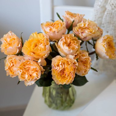 Turuncu gül buketi, suni taştan yapılmış pencere kenarındaki eski yeşil cam vazonun içinde..