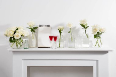 Beyaz şömine konsolunda cam vazoda duran beyaz güller. İç dekorasyon için bir melek figürü olarak. Uzayı kopyala Gül Beyaz Pembe O 'hara.