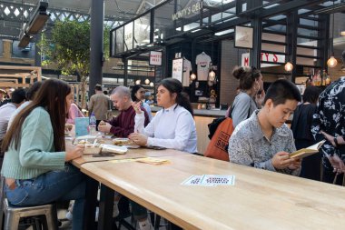 Londra, İngiltere - 20 Eylül 2020, İnsanlar Doğu Londra 'daki Spitalfields Market' in gıda salonunda yemek yiyorlar. İnsanlar dışarıda bira içer.