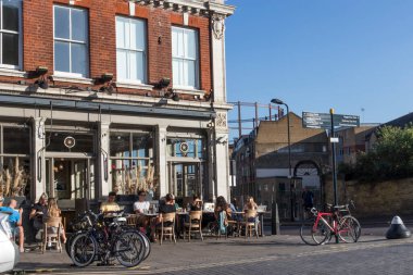 Londra, İngiltere - 20 Eylül 2020, İnsanlar Broadway Road 'un köşesindeki kanalın yakınında kahvaltı ediyorlar. Park edilmiş bisikletler. Parlak güneş