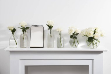 Beyaz şömine konsolunda cam vazoda duran beyaz güller. İç dekorasyon için bir melek figürü olarak. Uzayı kopyala Gül Beyaz Pembe O 'hara.